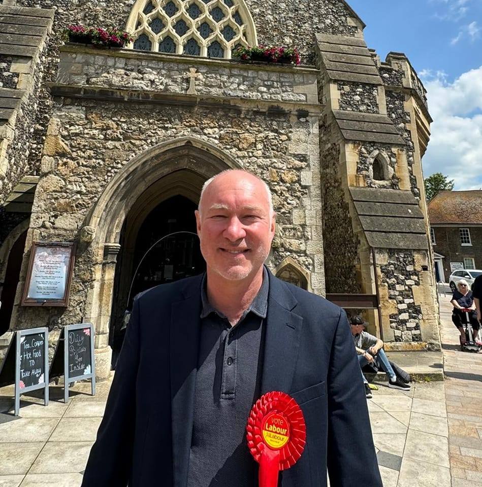 Jim Dickson MP, wearing red rosette, outside Holy Trinity Dartford
